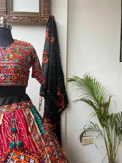 A close-up of this black and red chaniya choli. The hanging tassels on the skirt add a playful touch that moves with you as you dance.