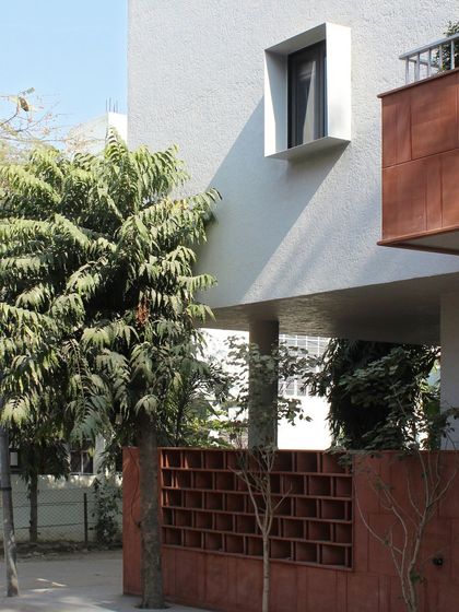A detail of the Jaipur House facade, showing the cantilevered volume and the punched window. This composition of simple geometric forms and natural textures is a hallmark of our warm minimalist design philosophy.