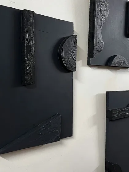 A detailed shot of one of the black textured panels. The contrast between the smooth background and the rough, sculpted additions creates a visually interesting piece.