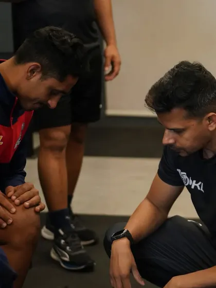 A one-on-one moment with a player, assessing his knee and discussing his physical state. Individual care is a cornerstone of my coaching.