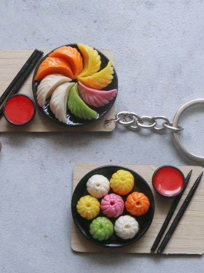 A pair of momo miniatures, one as a keychain and the other as a magnet.