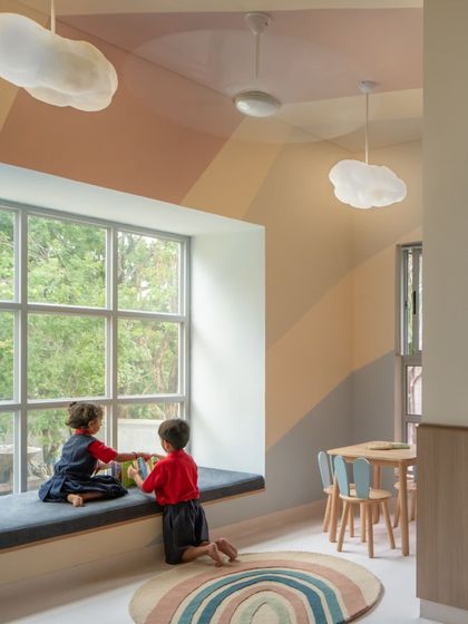 This reading nook under a painted rainbow and cloud-like pendant lights is a perfect example of how we create little pockets of magic. The window seat provides a comfortable spot for two friends to share a book.