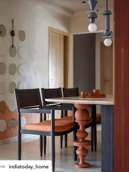 The dining area, featuring a travertine table with a unique turned wooden leg. The custom suspended lights and wall art add to the room's artistic and modern vibe.