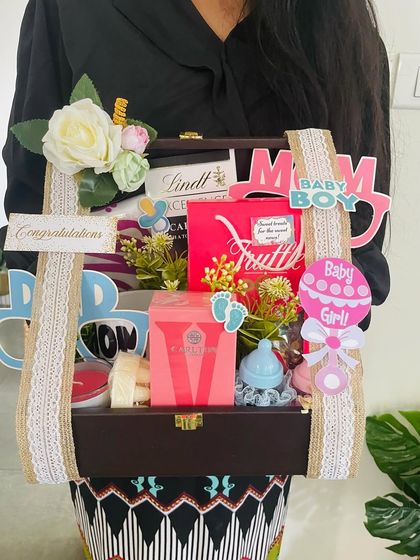 A close-up of the parents-to-be hamper, showing the mix of luxury chocolates for the parents and cute baby-themed items.