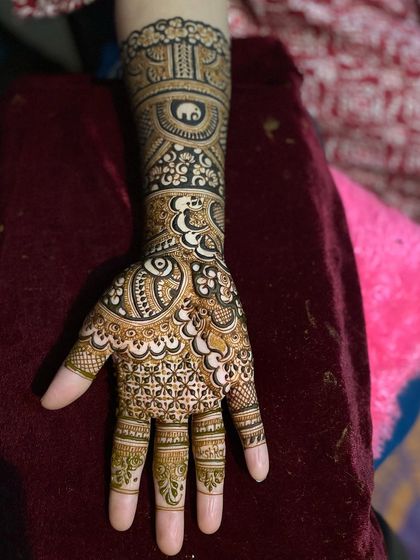 A completed practice design on a mannequin hand, showing a full Indian style pattern.