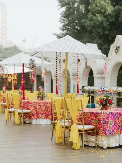A long shot of the guest dining area, with colorful tablecloths and decorative umbrellas. The entire setup is designed to be bright, cheerful, and perfect for a sunny daytime event.