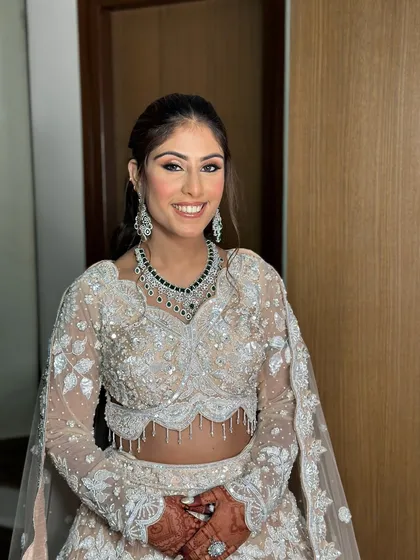 The complete look, showing how the soft glam makeup pairs perfectly with the intricate ivory lehenga and diamond jewelry.