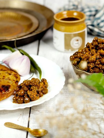 A deconstructed serving of the pickle with a piece of paratha on a white plate. This bright and airy shot offers a clean, modern take on presenting a traditional food item.