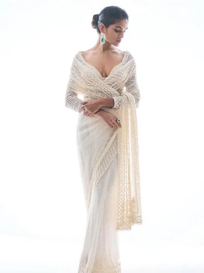 An ethereal white embroidered saree with a full-sleeve blouse. The look is one of pure elegance, perfect for a sophisticated evening affair.