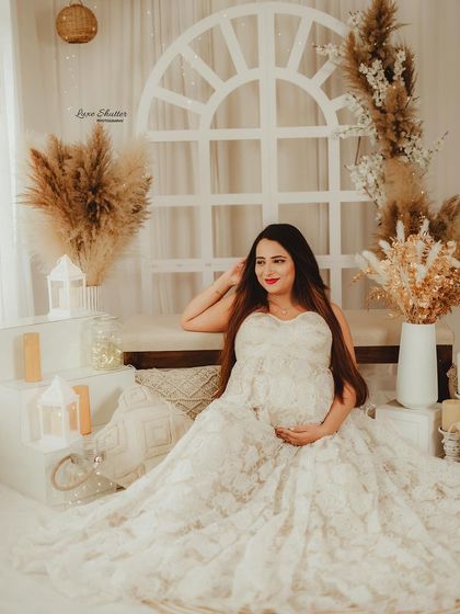 A full view of our cozy, boho-inspired studio set. The combination of the lace gown, warm lights, and natural textures creates a perfect setting for romantic maternity photos.