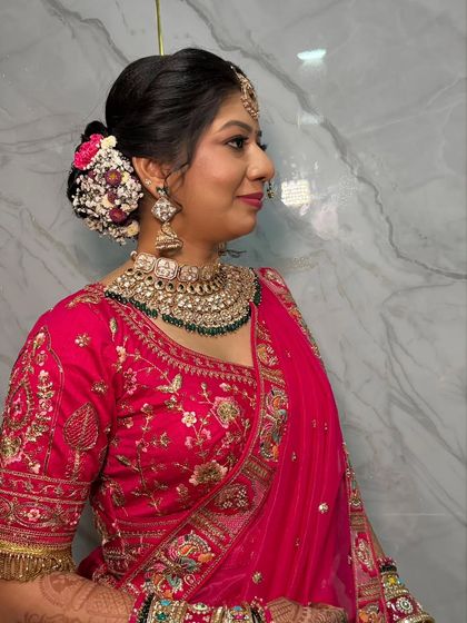 A side view highlighting the intricate floral bun and the flawless makeup. The details of her look, from the jhumkas to the maang tikka, are perfectly complemented by the makeup.