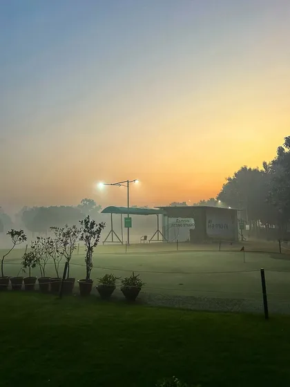 A misty morning view of the putting green and practice bays, creating a serene and beautiful atmosphere.