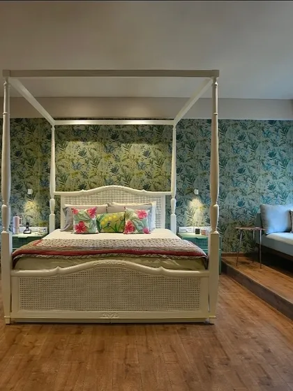 This bedroom is designed as a gentle, harmonious retreat. A classic four-poster bed is set against a wall of soft teal and green, creating a calm space where mornings begin in stillness, connected to the light from the window-side daybed.
