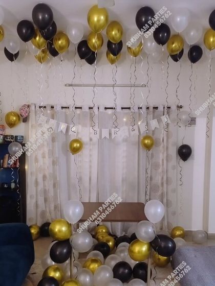 A classy home decoration with black, gold, and white balloons floating on the ceiling.