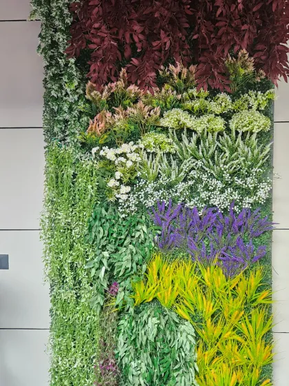 A beautiful example of an artificial plant wall with a mix of green, white, and purple foliage. This type of installation is perfect for adding a touch of nature to an indoor space where real plants might not thrive.