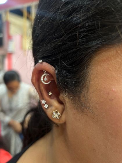 Another view of a celestial-themed stack, with a moon hanging, star stud, and a simple hoop. It's a popular and dreamy combination.