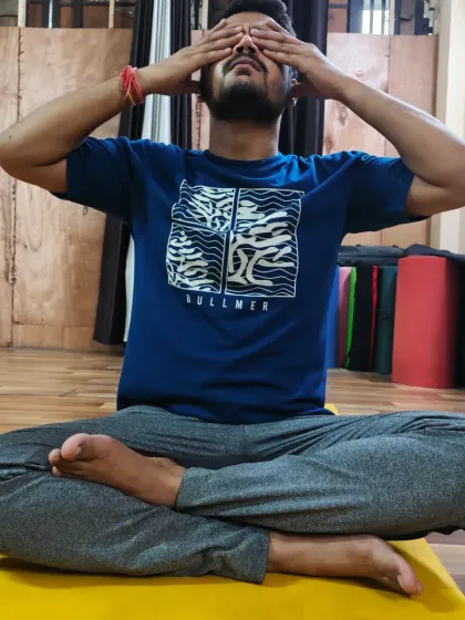 A male student practices Bhramari Pranayama, showing how this technique is beneficial for everyone seeking stress relief and mental peace.