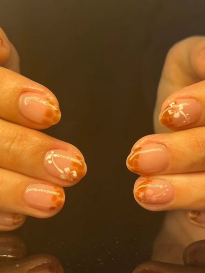 A delicate design with hand-painted floral patterns on a sheer nude base with amber-colored tips.