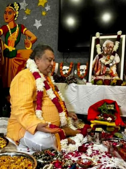 Guru Pt. Jai Kishan Maharaj ji during the Guru Purnima puja, surrounded by offerings and portraits of the great masters of our lineage.