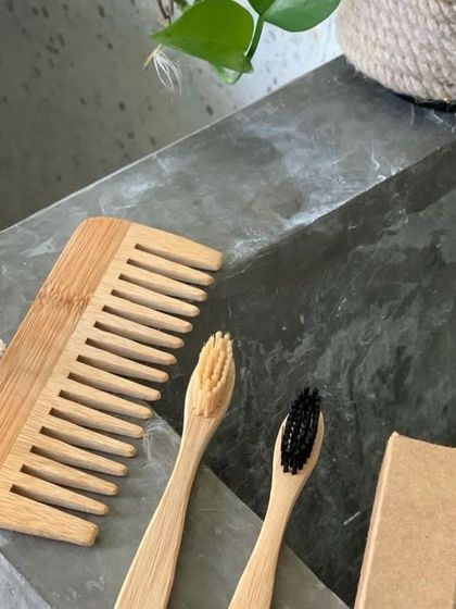 A close-up of our essential personal care swaps. This image features a wide-tooth bamboo comb alongside two bamboo toothbrushes, showcasing the natural materials and simple design of our eco-friendly alternatives.