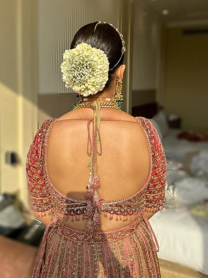 A detailed shot of the elegant floral bun, adding a touch of romance to the modern pink bridal look.