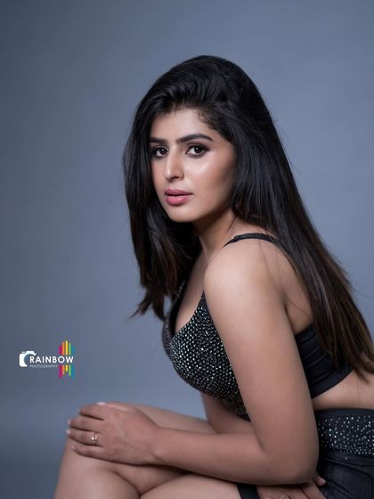 A powerful studio portrait featuring a sparkling black two-piece outfit. The simple grey background ensures all focus is on the model and her modern, edgy style.