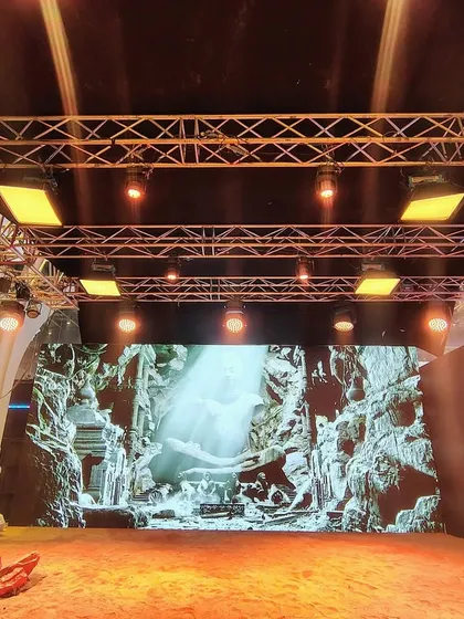 The virtual production stage at WAVES 2025 comes to life. The LED wall displays a dramatic cave environment, showcasing the photorealistic quality of the virtual sets we can create.