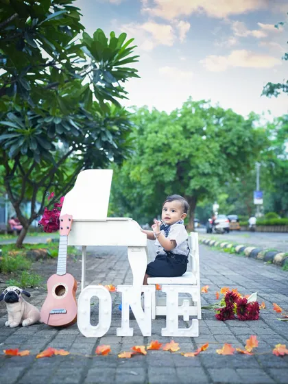Taking the celebration outdoors! For Krishiv's first birthday shoot, we set up this mini piano and 'ONE' sign in a beautiful Navi Mumbai park. Outdoor shoots add a lovely natural element to milestone memories.