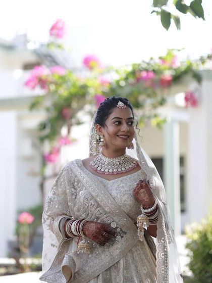 A full view of our client looking ethereal in a white lehenga, complemented by the American diamond and pink stone set she rented.