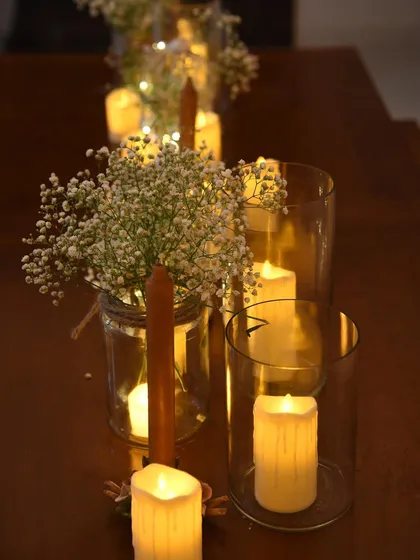 A close-up of the tablescape, featuring baby's breath in mason jars alongside pillar candles in glass hurricanes. Simple elements combined to create a truly magical effect.