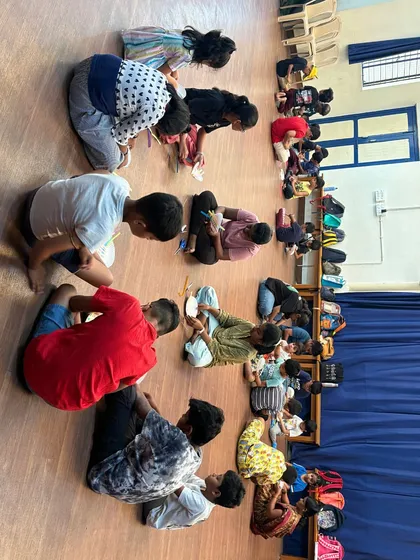 A long row of students, seen from above, are deeply engaged in their craft projects. This image showcases the calm focus that children can achieve when they are absorbed in a creative task.