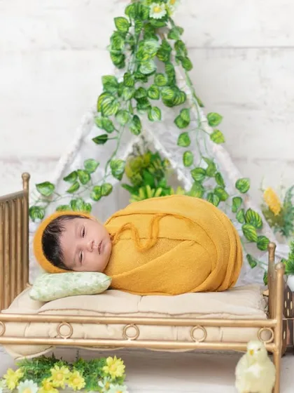 This little one is wide awake and curious in this yellow-themed setup on a tiny bed.