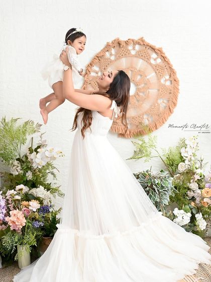 A mother's love captured in a single frame. Lifting her daughter up in the air, surrounded by soft florals, this image is full of light, joy, and tenderness.