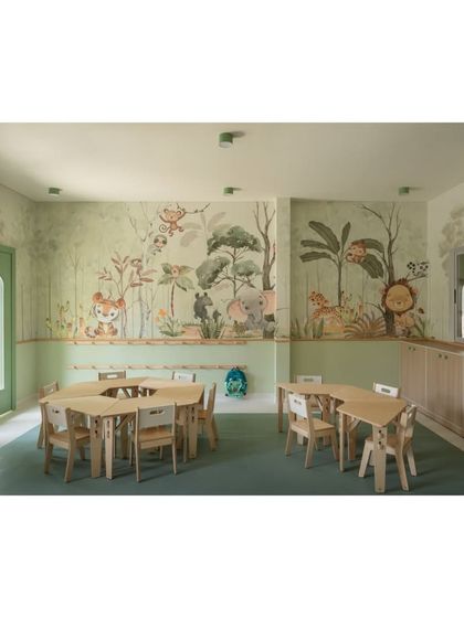 This wide shot of the forest classroom shows how the detailed wallpaper creates a complete, immersive environment. The space is filled with natural light, and the green flooring ties the whole theme together.