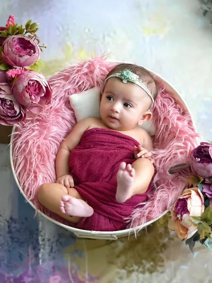 Celebrating milestones, big and small. This baby girl, nestled in a bowl of pink fur and flowers, is a picture of sweetness.