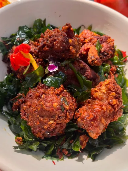A close-up of our special chicken fry, served on a bed of crispy fried curry leaves. The dish is adorned with edible flowers, making it a feast for the eyes as well.