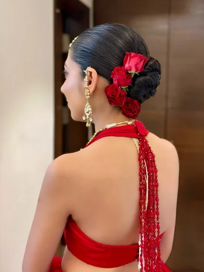 The back view of this stunning floral bun. The vibrant red roses against the sleek black hair create a look that is both classic and dramatic.