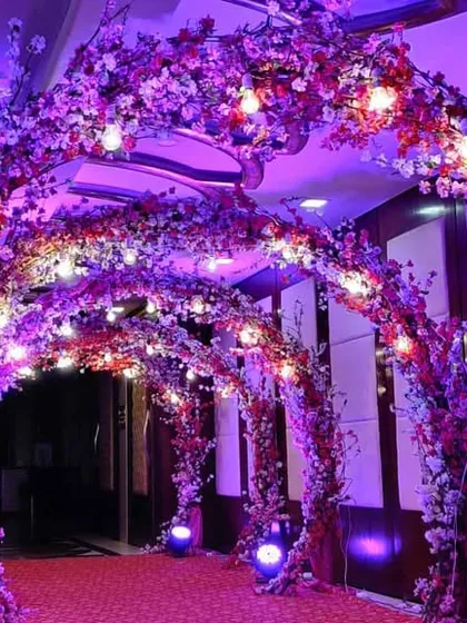 A breathtaking floral tunnel for a Sangeet night entrance. We covered the arches completely in purple and pink flowers, with warm lights nestled within to create a magical, immersive experience.