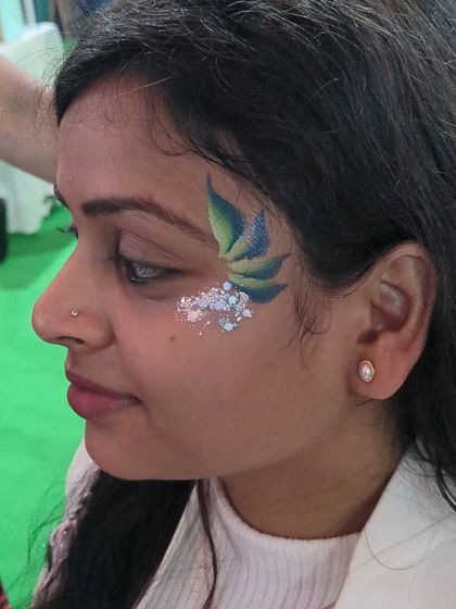 An abstract design with green and blue leaf-like shapes, accented with silver glitter.