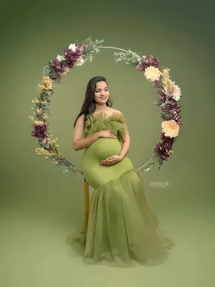 This elegant shot features a large floral hoop, framing the mother-to-be in our olive green gown. The prop adds a beautiful circular element to the composition, symbolizing wholeness and life.