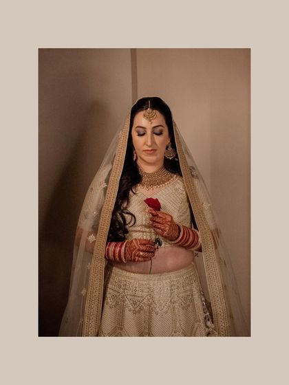 A full-length portrait of the bride holding a red rose. Her serene expression and the classic composition create a beautiful and poignant image.