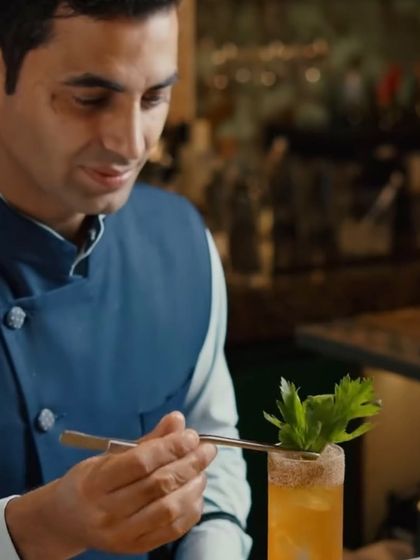 The final, delicate touch. Varun garnishes a cocktail with fresh celery, adding an aromatic finish to his creation.