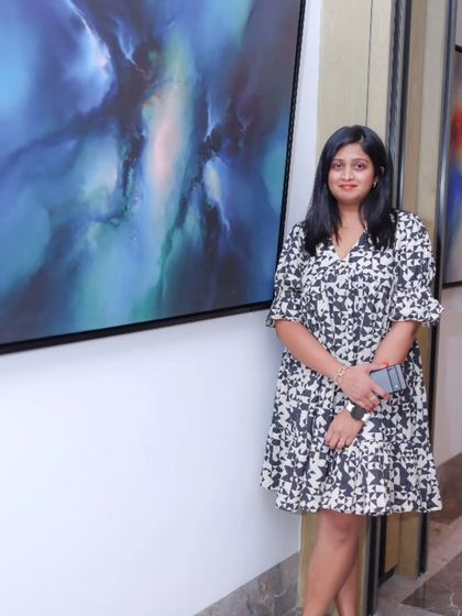 A visitor posing with a stunning blue abstract painting from the 'Mystic Mirage' exhibition.