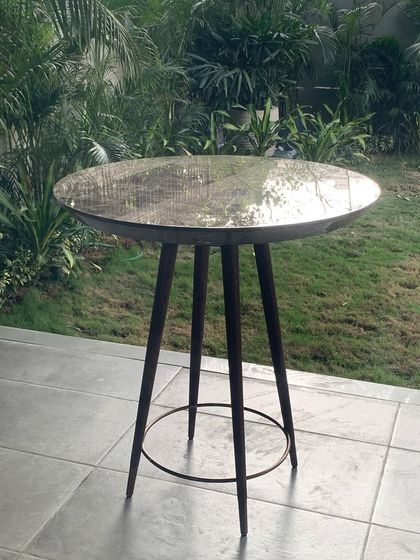 A simple yet elegant high-top table with a textured metal surface sits on an outdoor patio. This detail reflects my focus on selecting furniture and objects that have a handcrafted quality and a timeless appeal.
