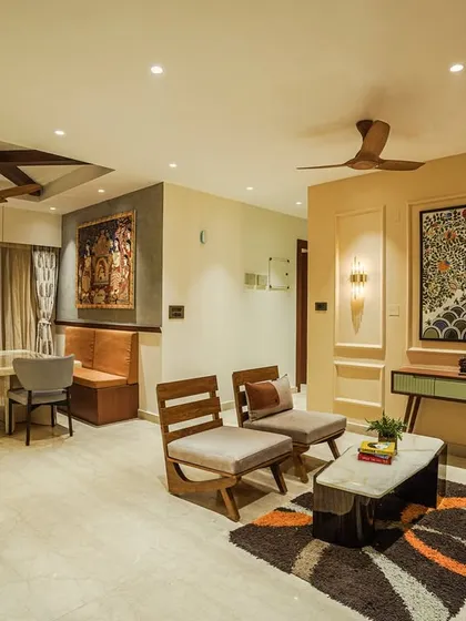 An open-plan living and dining area featuring a stunning Madhubani art piece, tan leather sofa, and a dining nook with bench seating.