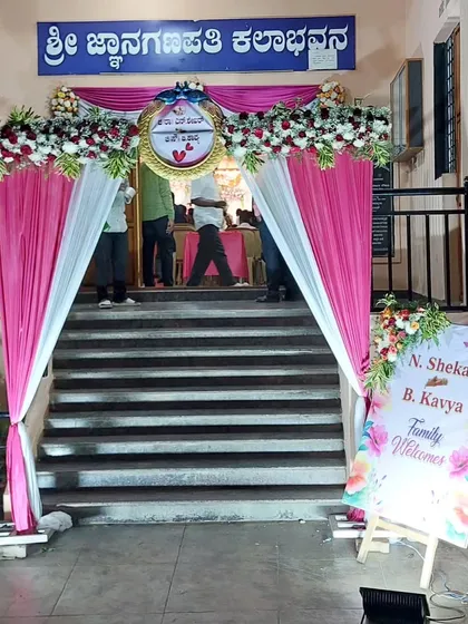 We make sure your guests feel welcome with a grand entrance. At the Sri Jnanaganapathi Kalabhavana, we created an elegant entryway with pink and white drapes, floral arrangements, and a personalized welcome easel for the family.
