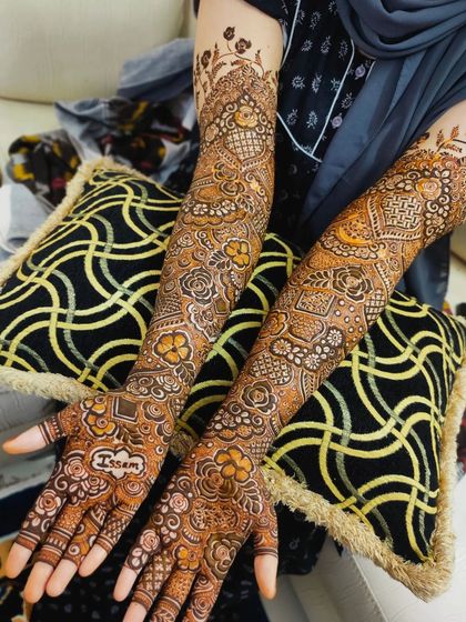 A beautiful bridal design with the name 'Issam' on the palm, surrounded by a dense floral pattern.