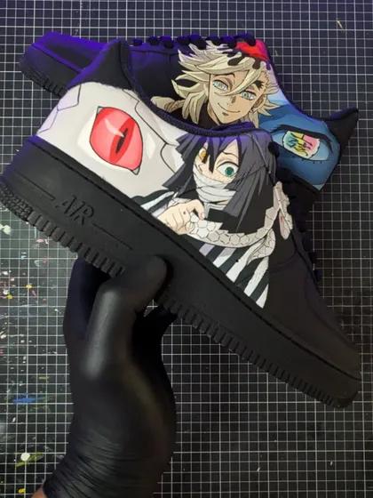 A Demon Slayer face-off between the Serpent Hashira, Obanai Iguro, and the formidable Upper Moon Two, Doma. The contrasting characters make for a dynamic design on these black AF1s.