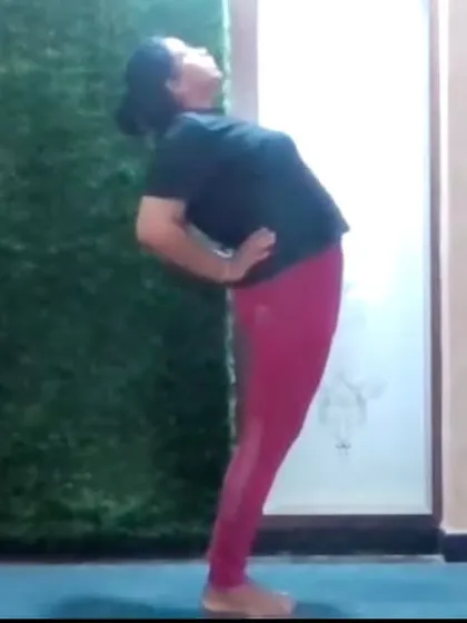 An instructor demonstrates a standing backbend, a preparatory pose for deeper backbends. We focus on building strength and flexibility progressively and safely in our online classes.