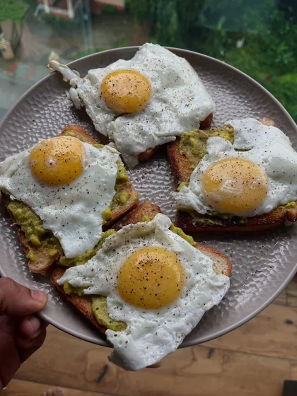 A classic breakfast: avocado toast topped with four sunny-side-up eggs. This is a simple, high-protein way to start the day.